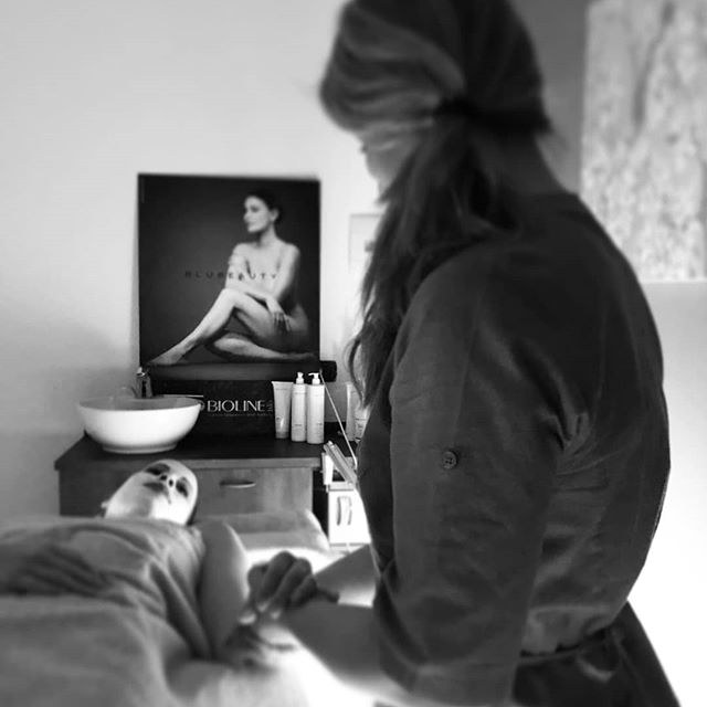 Un’operatrice al lavoro in cabina, in bianco e nero, con una cliente distesa con la maschera