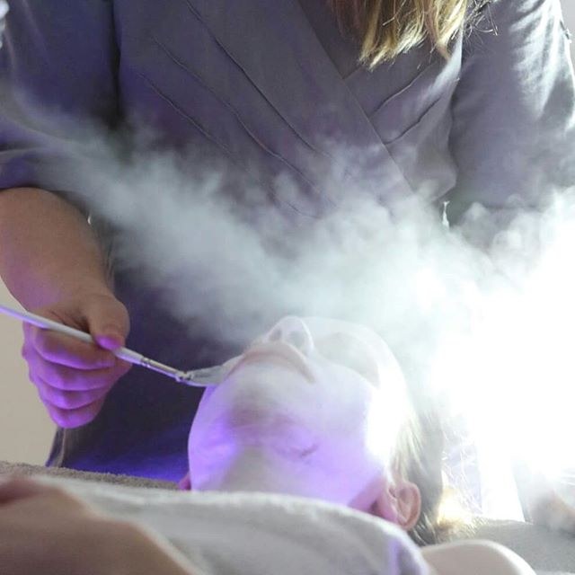 Il vapore avvolge il viso di una cliente mentre l’operatrice lavora con un pennello